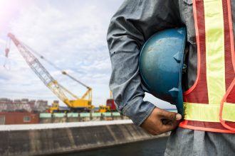 construction worker holding a hard hat at a construction site