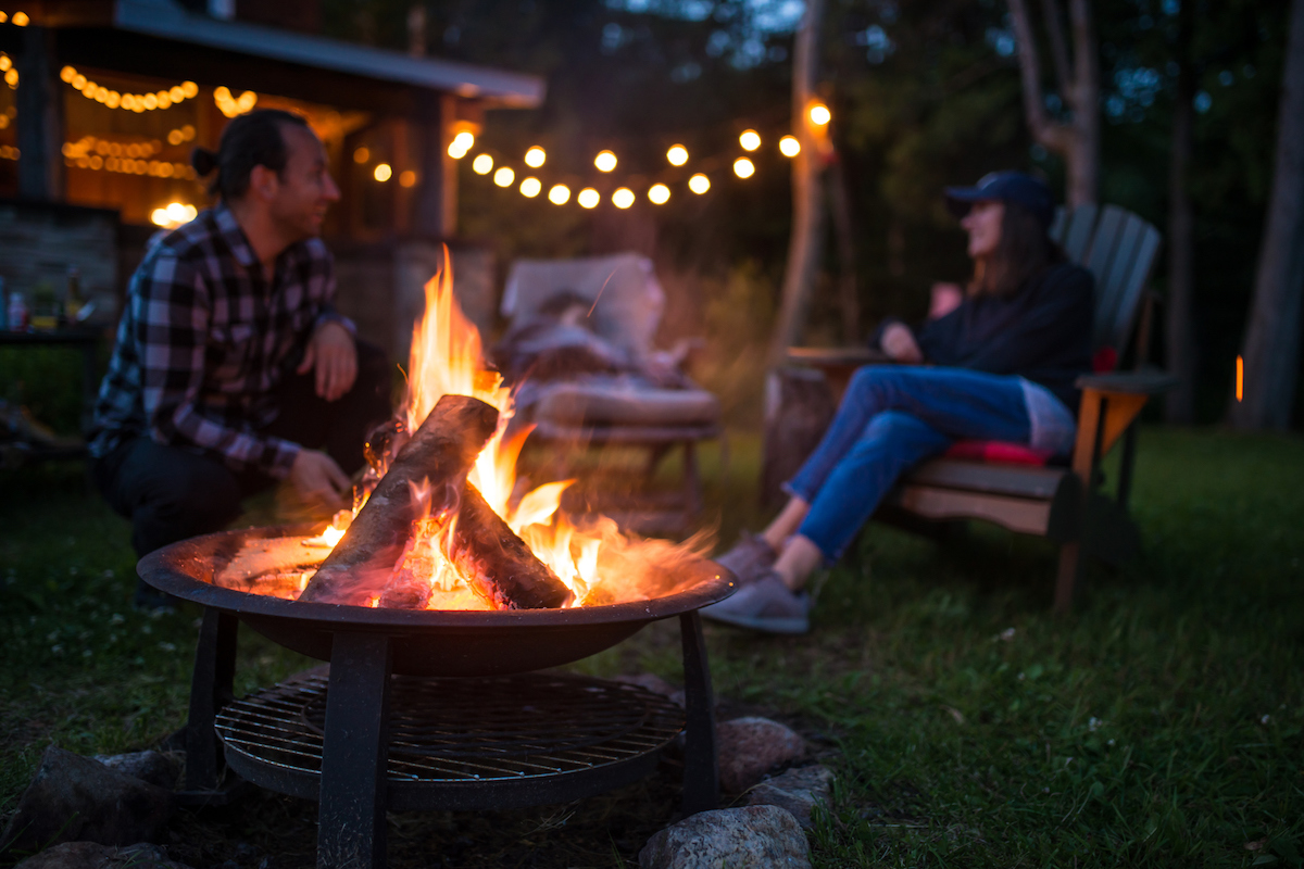 Young family is warming near campfire late evening at a beatiful canadian chalet