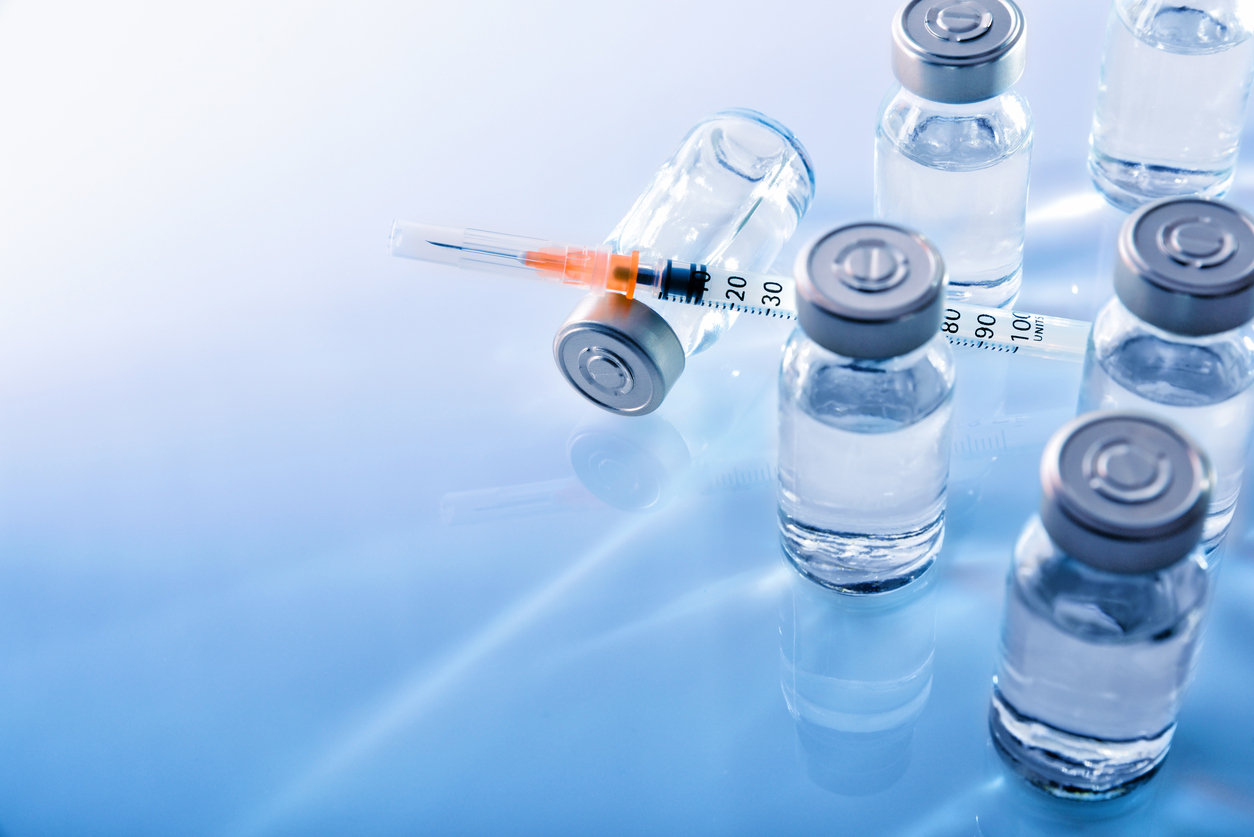Vials with medication and syringe on blue methacrylate table. Horizontal composition. Top elevated view.