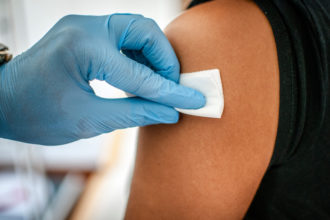 Doctor disinfects skin of patient before vaccination