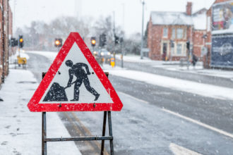 construction warning site on the sidewalk with a winter town backdrop
