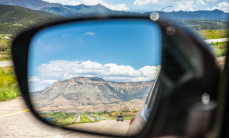 Driving through Colorado framing a mountain in the rearview mirror