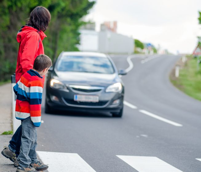 a woman and a child wait to cross the street