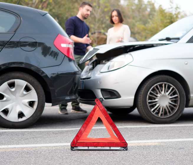 a pair converse between two cars that have crashed into one another