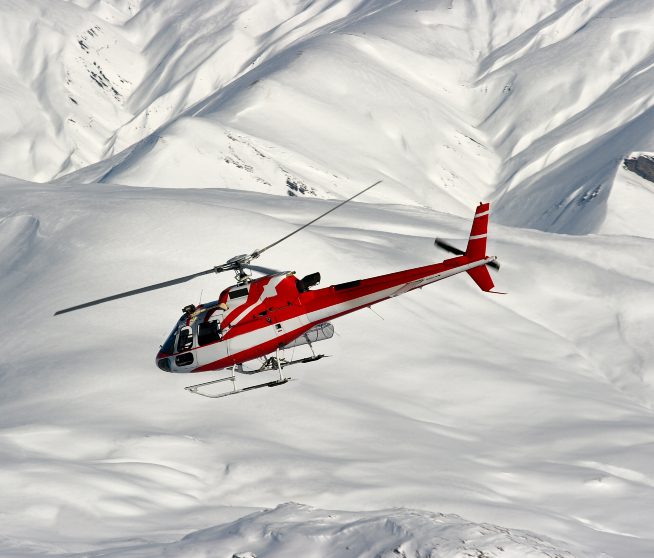 a helicopter descends on a snowy mountaintop