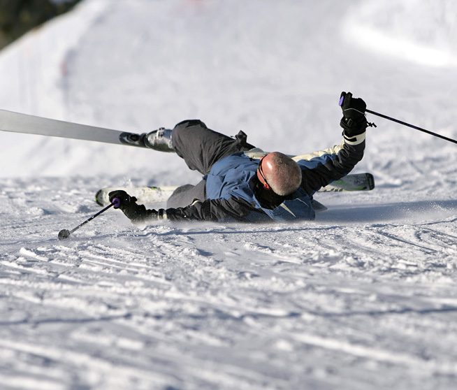 a skier lies on his back after falling in the snow