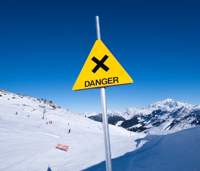 a yellow danger sign on a snowy mountain