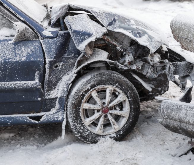 crushed front of car covered in snow