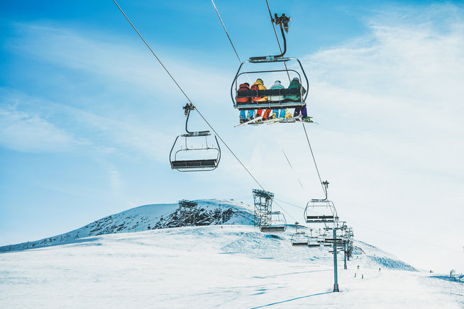 People on ski lift in winter ski resort - Holidays, snow gear renting, skiing, snowboarding and mountain landscape concept - Focus on guys sitting in cable car