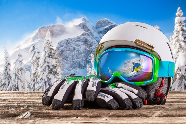 Colorful ski glasses, gloves and helmet on wooden table. Winter ski theme.