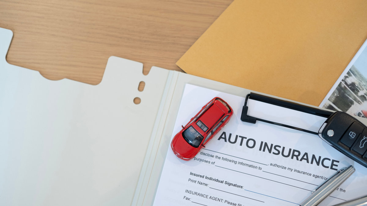 Vehicle insurance paperwork with pen black key and red car toy symbolizing accident claim financial protection safe driving legal coverage and long term stability
