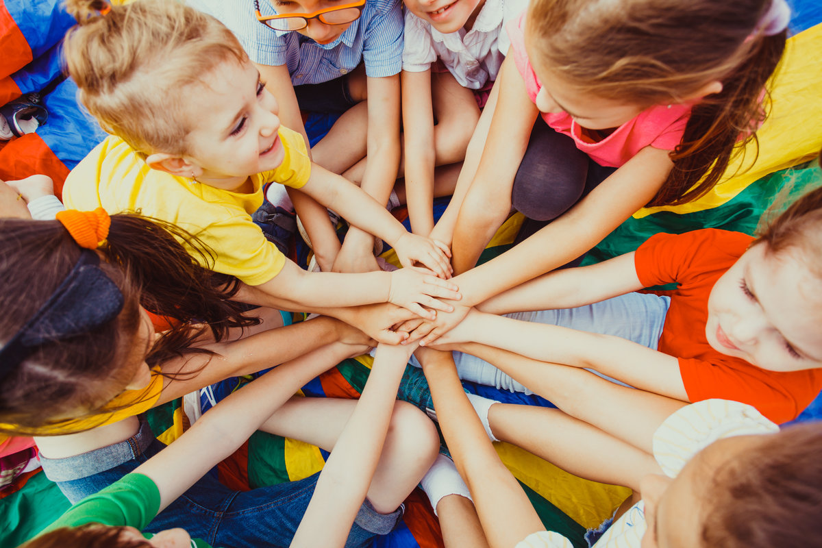 Group of children putting their hands together on a colorful background. Diversity concept