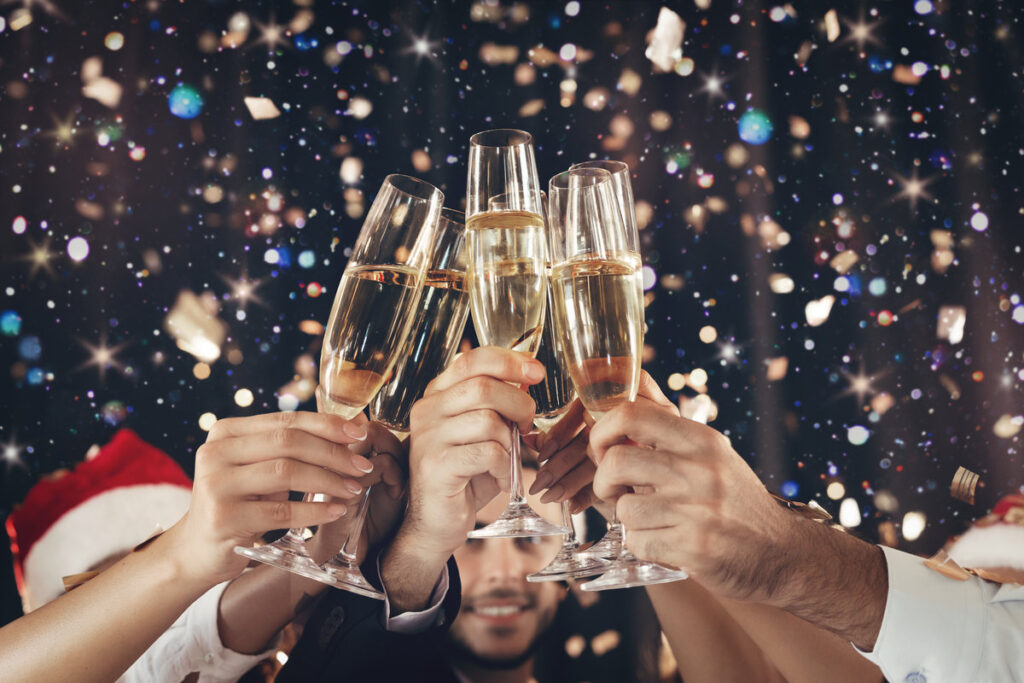 Happy New Year. Clinking glasses of champagne in hands on bright lights background