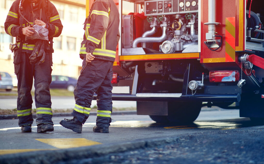 Profesional Fire truck with fire fighting equipment and firemen in protective clothing, helmets and mask.
