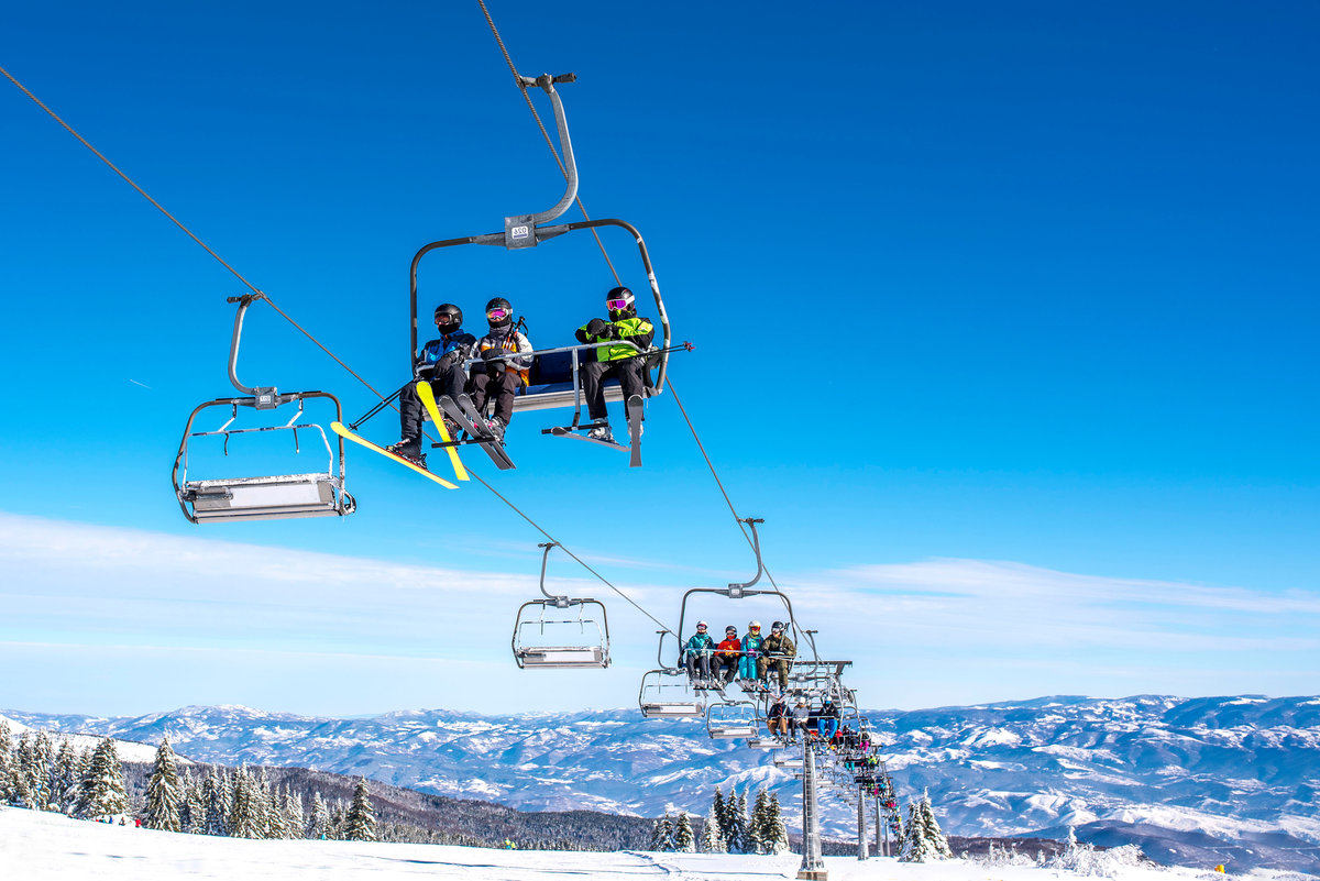 Skiers on chairlift at mountain ski resort with beautiful winter landscape in the background