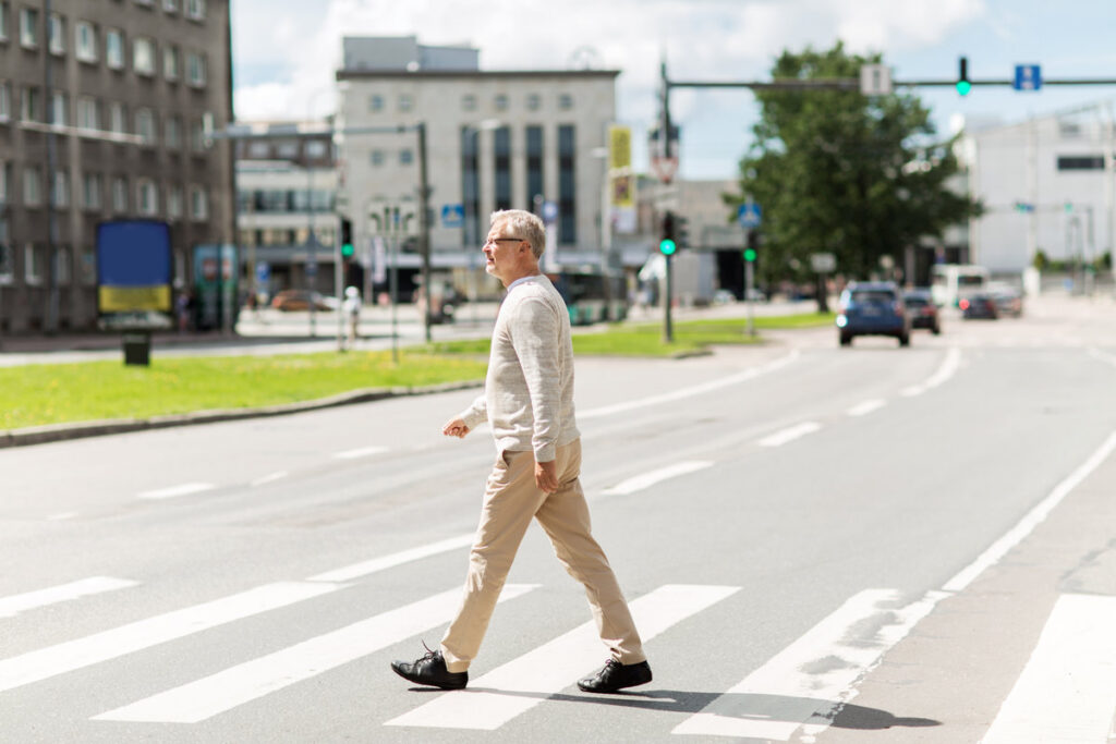leisure and people concept - senior man walking along summer city crosswalk