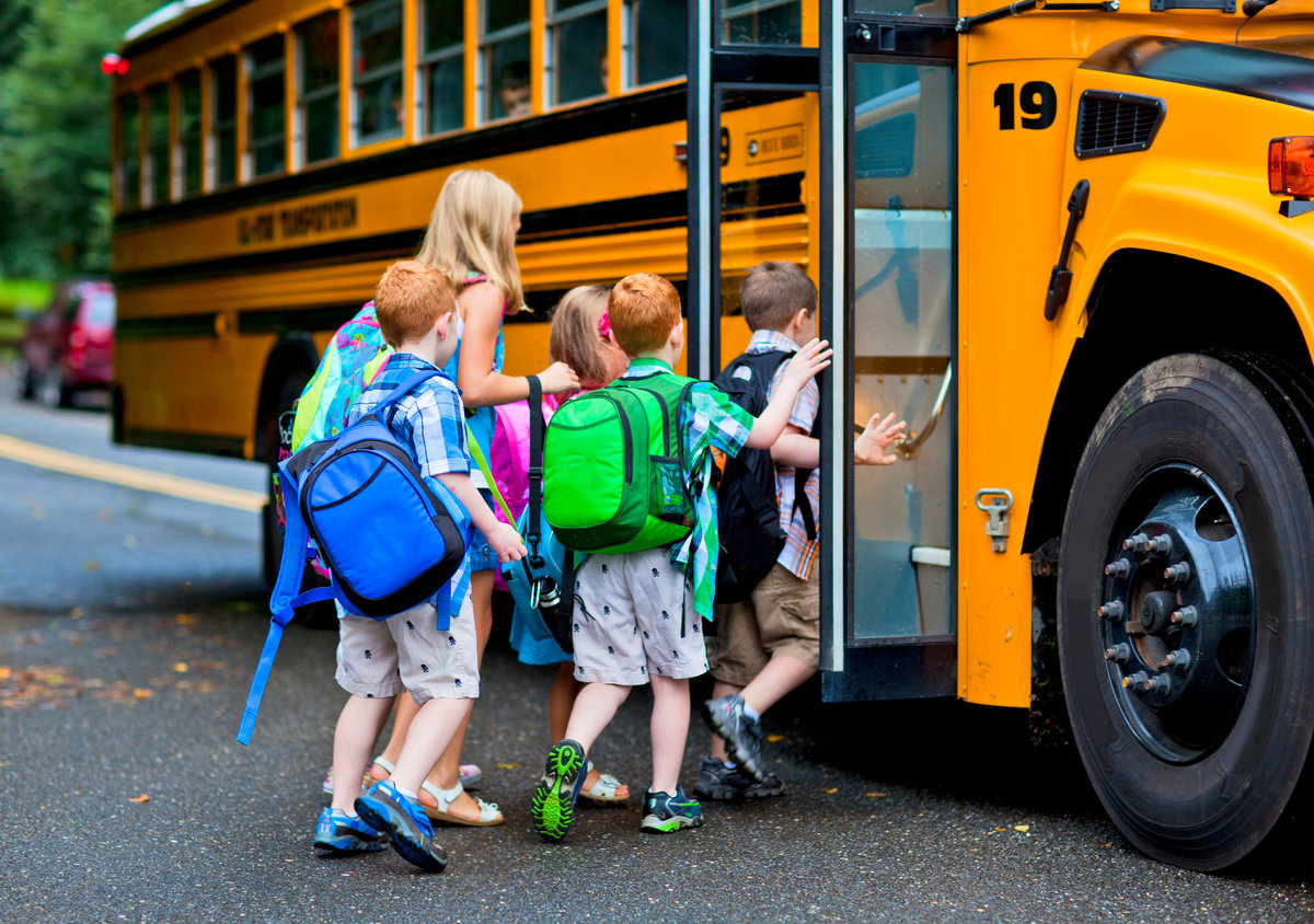 A group of young children getting on the schoolbus