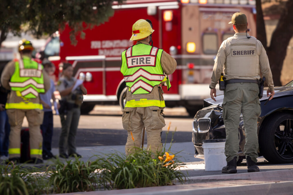 A police officer and a firefighter standing next to each other at a car accident scene