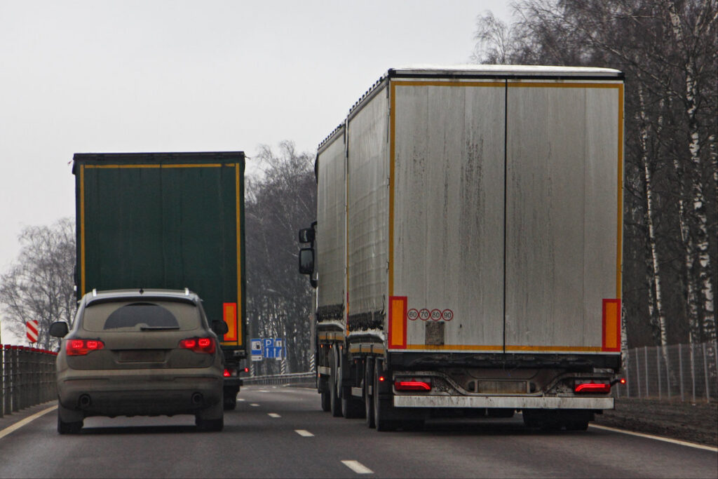 Suburban road traffic, a car in a hurry to overtake slow trucks in the left lane